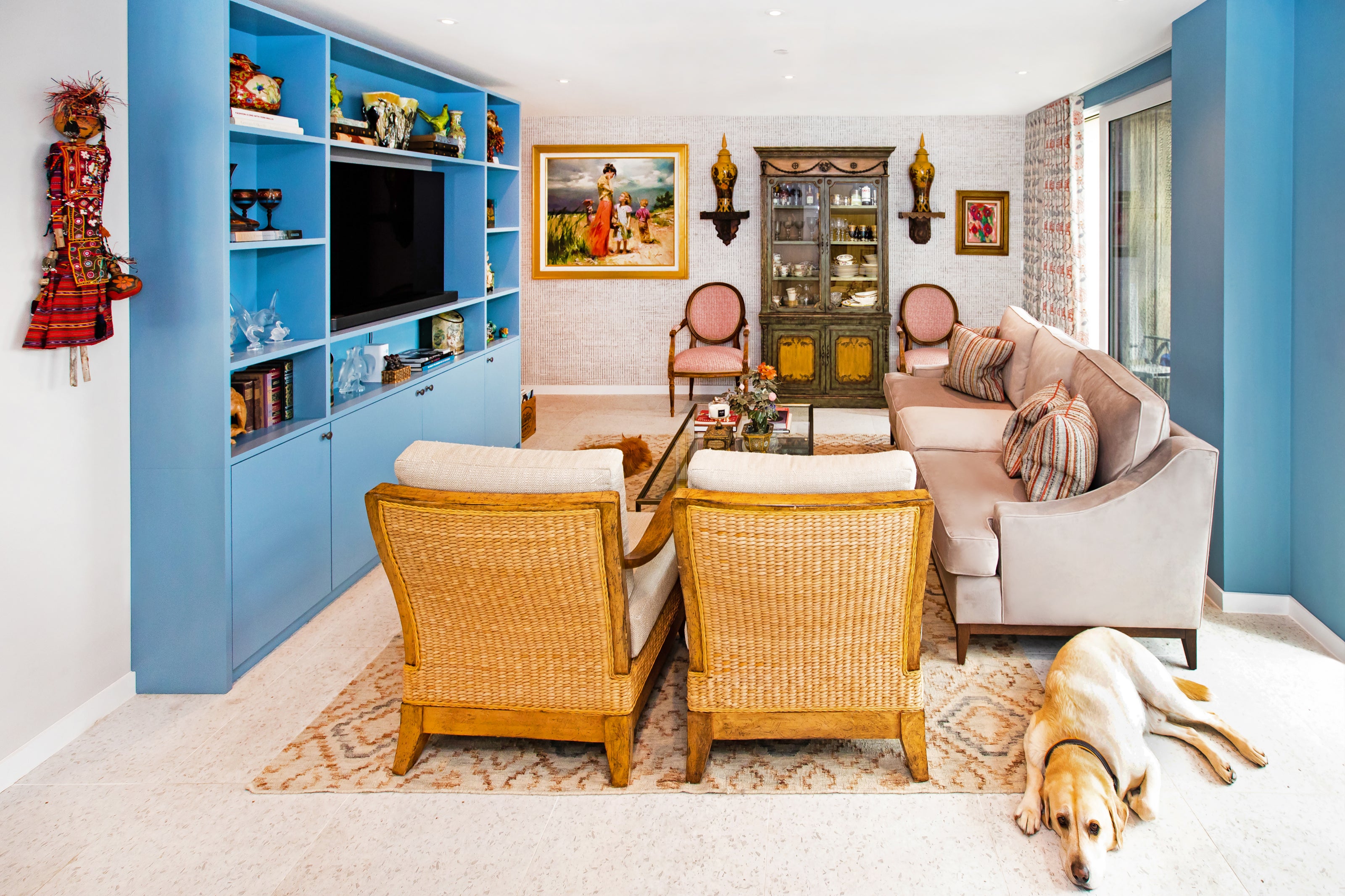 Living room with blue shelves, wicker chairs, and a beige sofa.