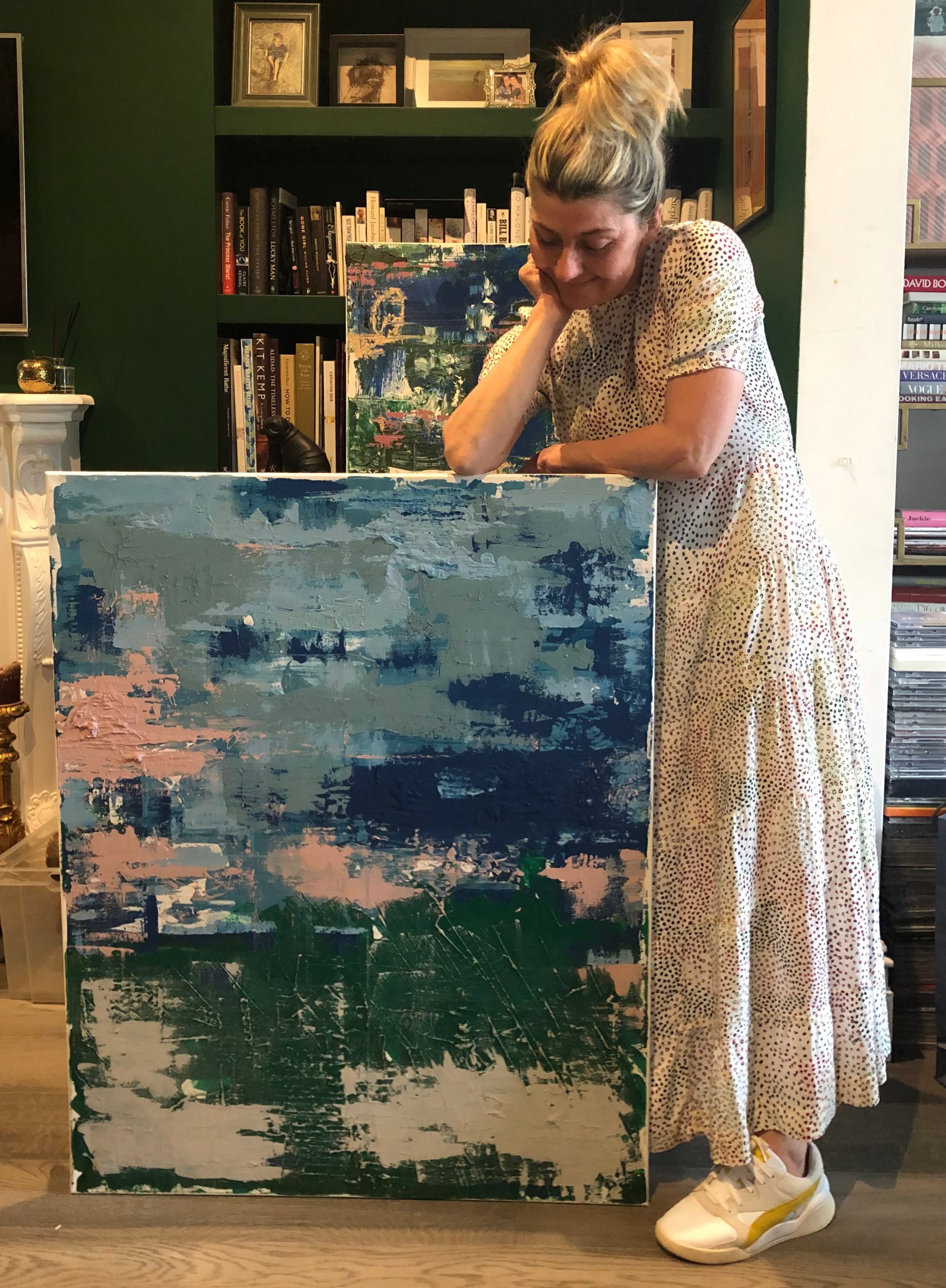fleur ward holding a large abstract painting in a room 