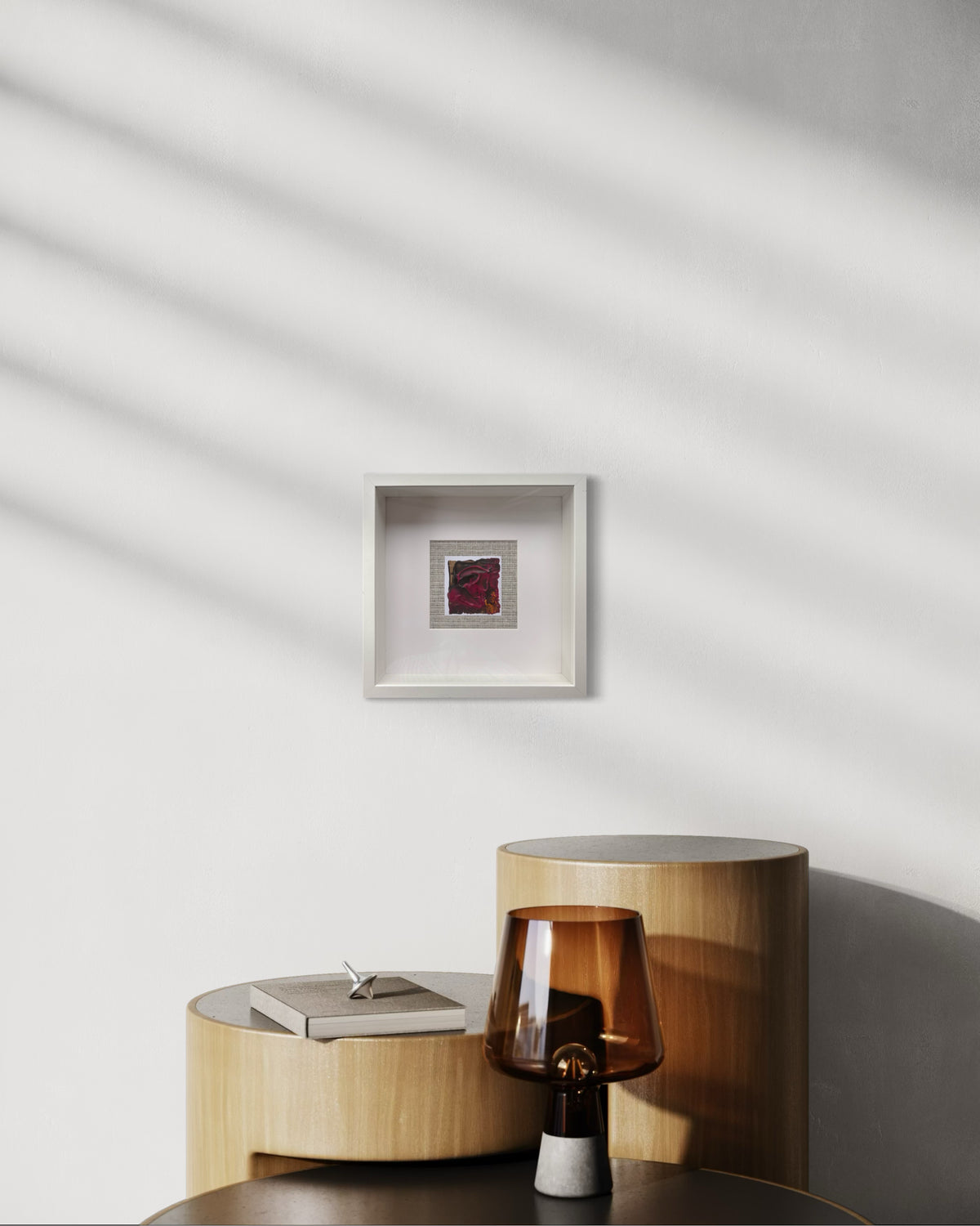 Explores the tension between depth and luminosity. Layers of rich crimson, blackberry and charcoal drift across the surface, interrupted by flashes of amber that emerge like embers beneath the paint. Mounted against a woven grass cloth backdrop, the work brings together texture, colour and materiality — a nod to Fleur Ward’s background in interiors, where surfaces and atmosphere are as important as form. The result is a piece that feels both organic and expressive, inviting the viewer to discover their own 