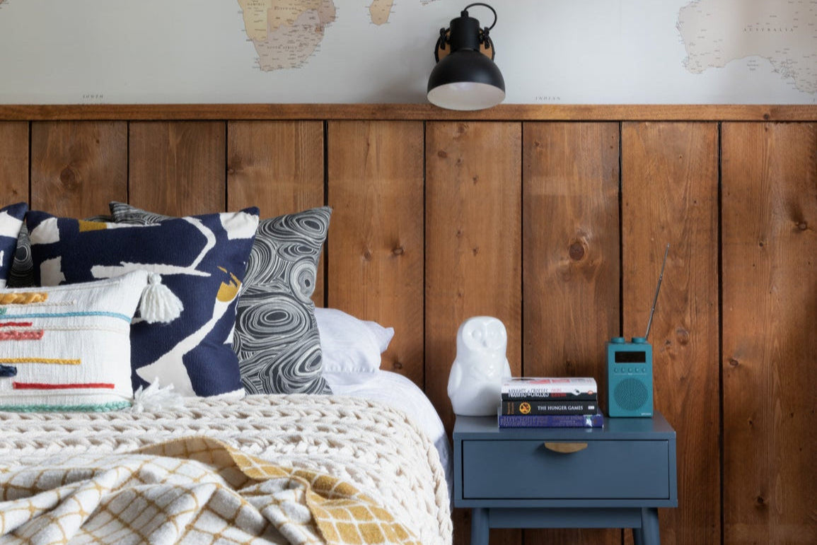 Bedroom with wooden headboard, pillows, and a nightstand with a radio.
